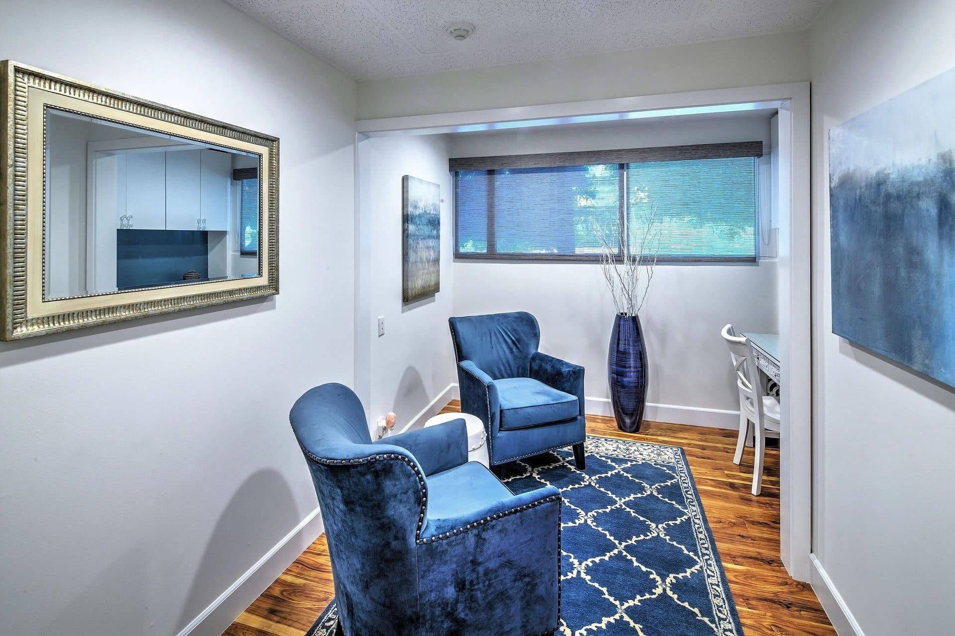 A quiet consultation room with blue velvet armchairs and a writing desk