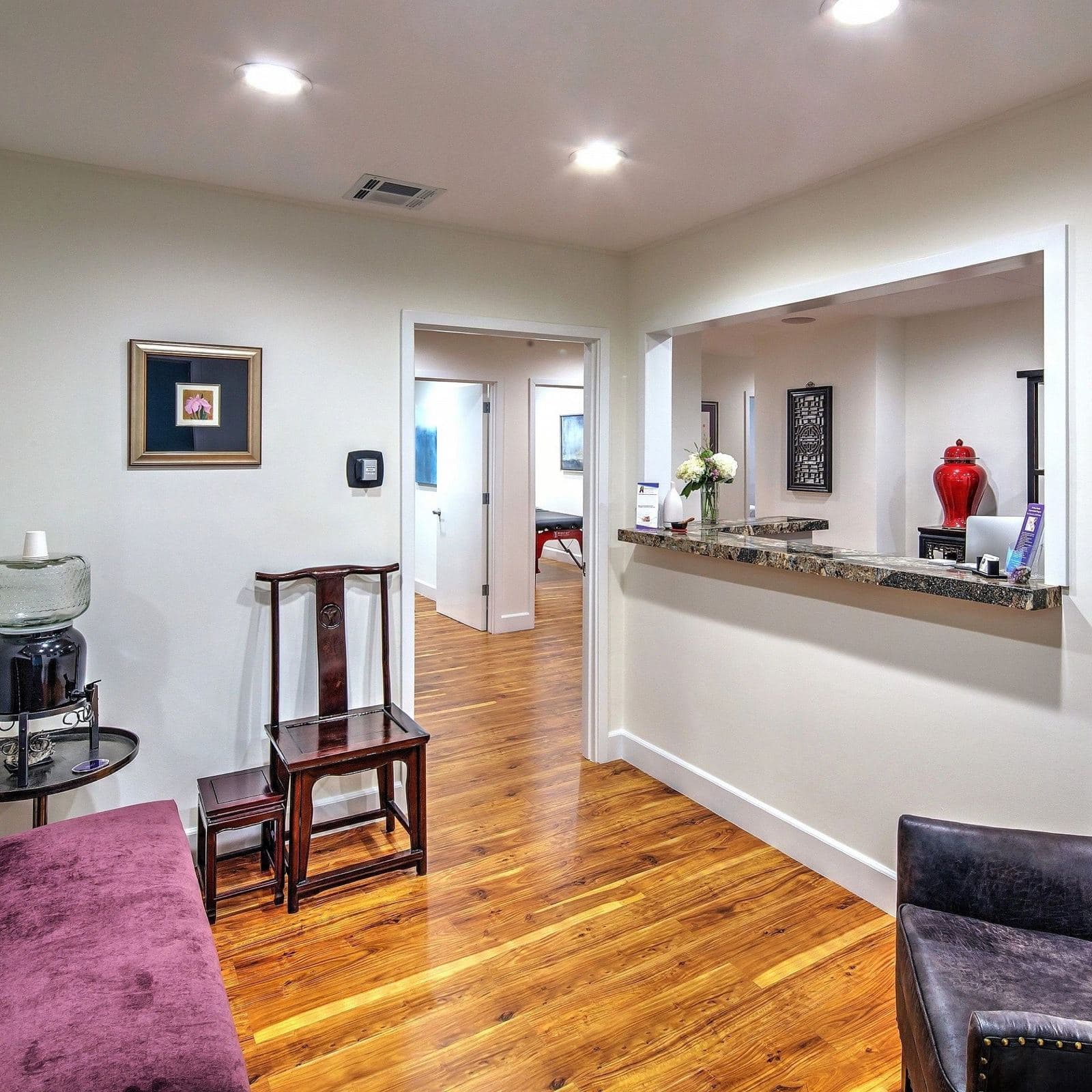 The waiting area, with warm wood floors, rosewood chairs, and fresh flowers at the front desk